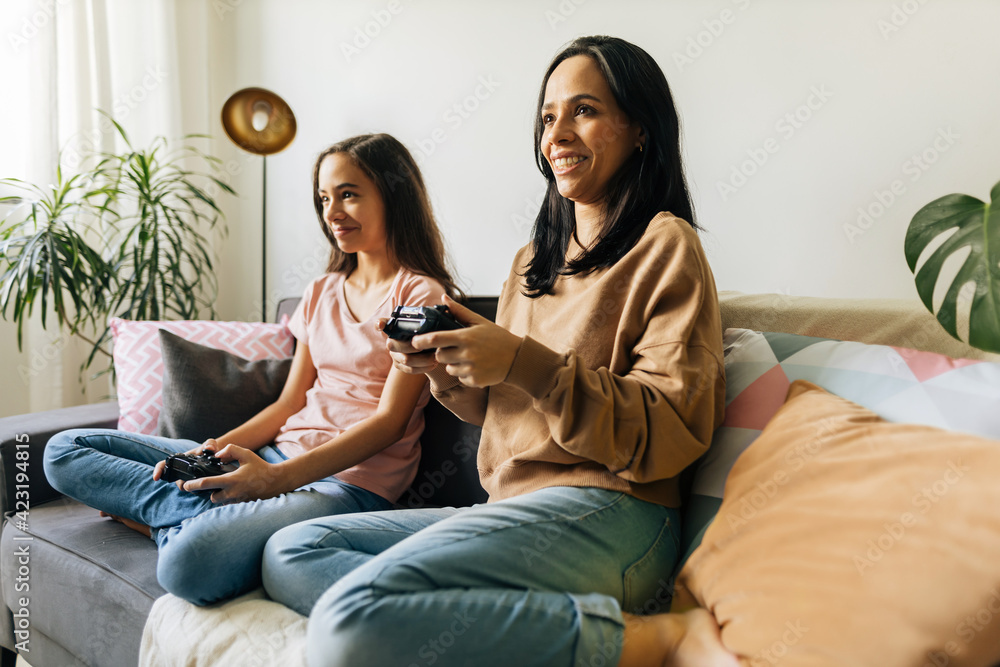 Single parenthood. Mother and daughter playing video games together at home. Single parenthood. Mother and daughter playing video games together at home.