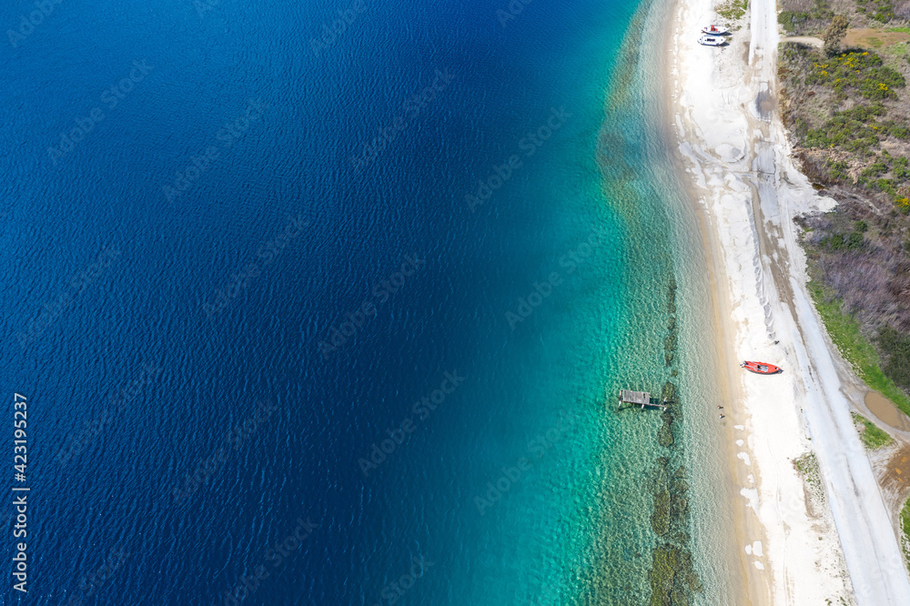 Aerial panorama of Mediterranean sea coast with white sand beach road and blue water. Top view of sail boat and pier with copy space summer tropical background