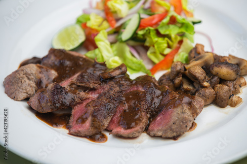 Juicy beef tenderloin steak sliced on a plate with vegetable salad