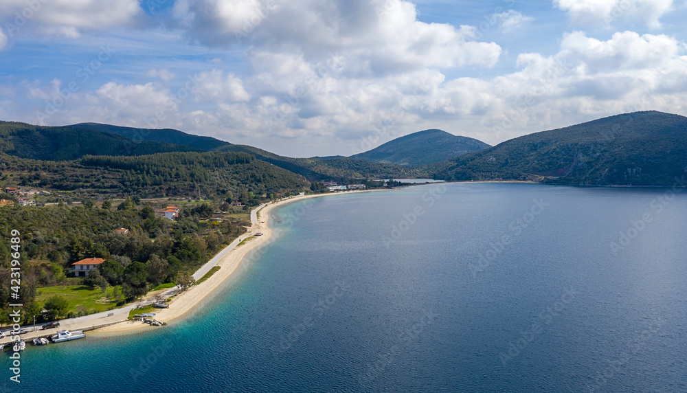 Panoramic top view on blue water sea coastline of Greek tourist island with green trees forest nature and white cloudy sky background