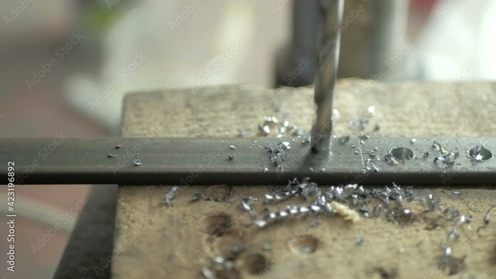 A man specializes a driller drilling holes on a drilling machine in a metal workpiece A man specializes a driller drilling holes on a drilling machine in a metal workpiece