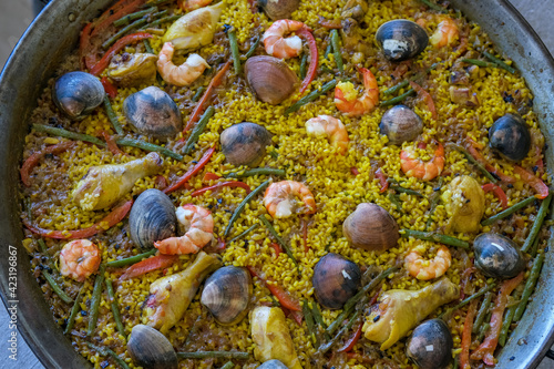 Cooking traditional spanish mixed paella with seafood and chicken in large pot or pan