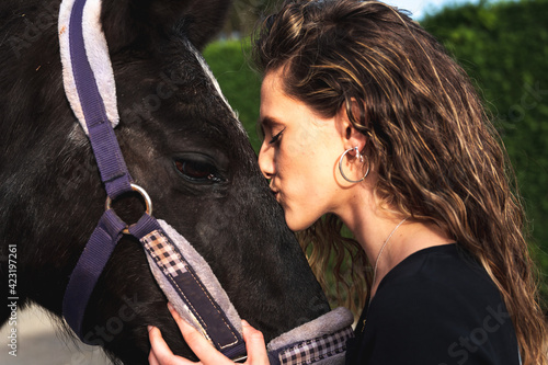 Young caucasian woman kissing a horse