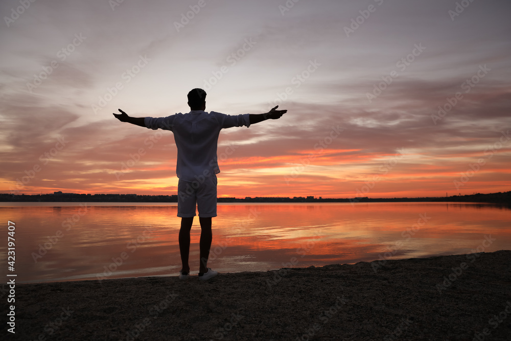 Man near river at sunset, back view. Nature healing power