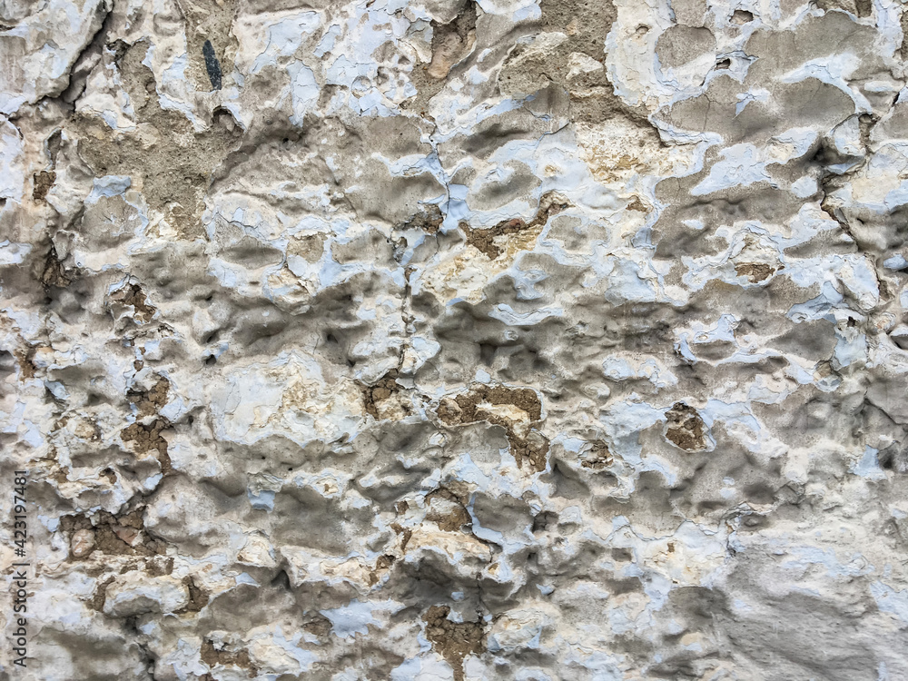rough stone wall with cracked blue, gray and white paint and cement rough stone wall with cracked blue, gray and white paint and cement