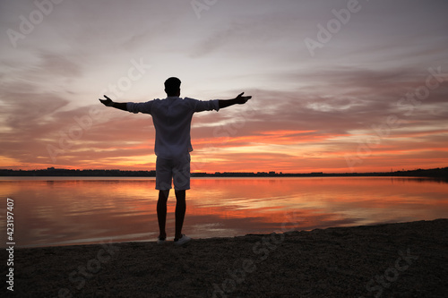 Man near river at sunset  back view. Nature healing power