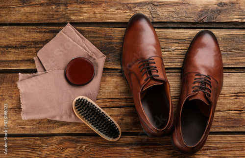 Flat lay composition with shoe care accessories and footwear on wooden background