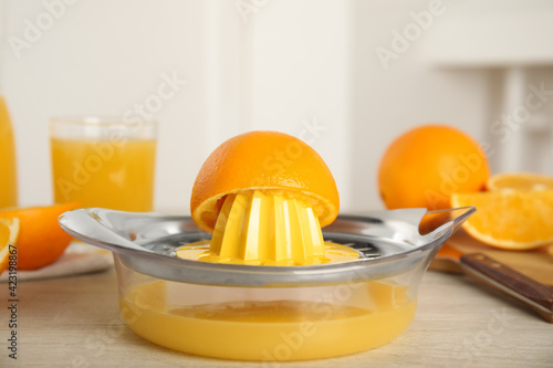 Cut fresh ripe orange and squeezer on wooden table