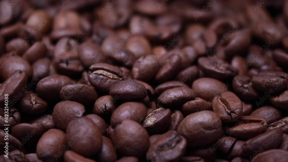 Close Up of Roasted coffee bean. Fragrant coffee seeds are falling in Slow Motion from above on a pile of Coffee seeds. Arabica, Robusta Close Up of Roasted coffee bean. Fragrant coffee seeds are falling in Slow Motion from above on a pile of Coffee seeds. Arabica, Robusta