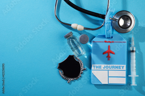 bottle of covid19 vaccine stethoscope lugagge tag and syringe isoltaed blue background photo