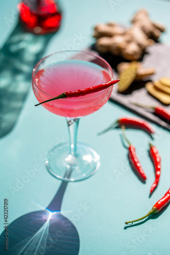 Bilde på lerret A cocktail in a glass with red chilly pepper and a cutting board with pepper, ginger ingredients  at the background