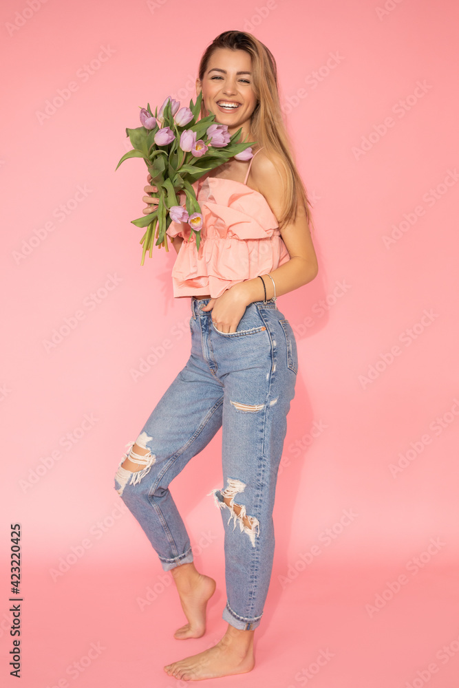 Photo of smiling Beautiful woman holding bouquet of spring flower tulips. Full-length studio shot on pink background. Gift, womens day concept Photo of smiling Beautiful woman holding bouquet of spring flower tulips. Full-length studio shot on pink background. Gift, womens day concept