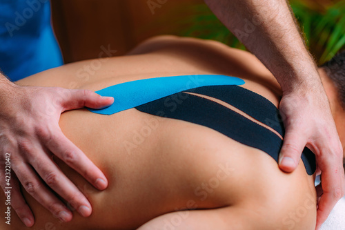 Kinesiology or Kinesio Tape Application. Physical Therapist Placing Elastic Therapeutic Tape on Patient’s Back