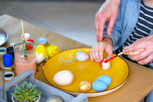 Little boy painting wooden eggs for Easter decoration