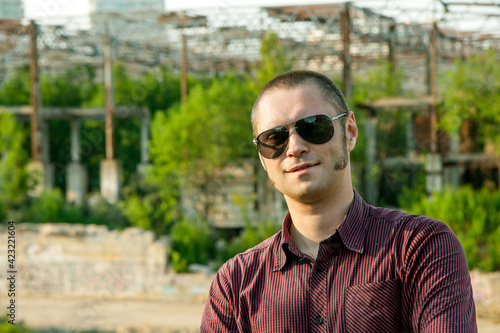 Obraz na plátne A man in a plaid shirt and sunglasses with sideburns in an abandoned building fo