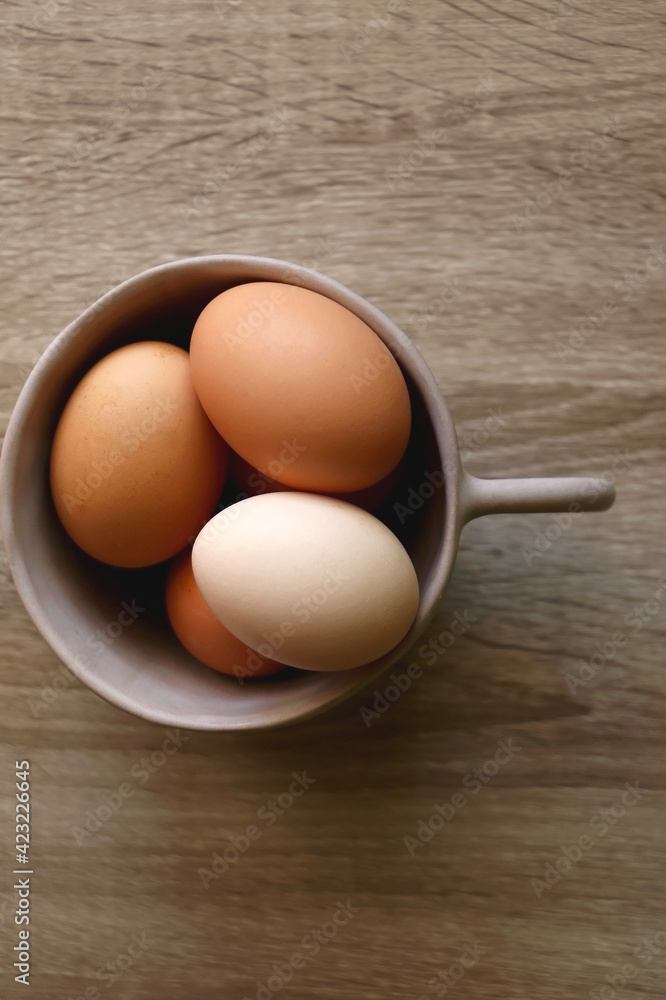 Ceramic bowl filled with fresh free range eggs on wooden table. Flat lay. Ceramic bowl filled with fresh free range eggs on wooden table. Flat lay.