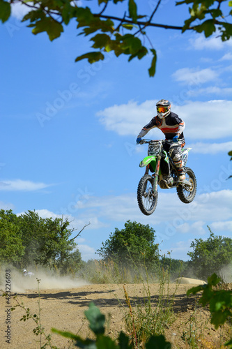 Motocross Rennen, Motorradfahrer springt mit Enduro durch die Luft bei blauem Himmel