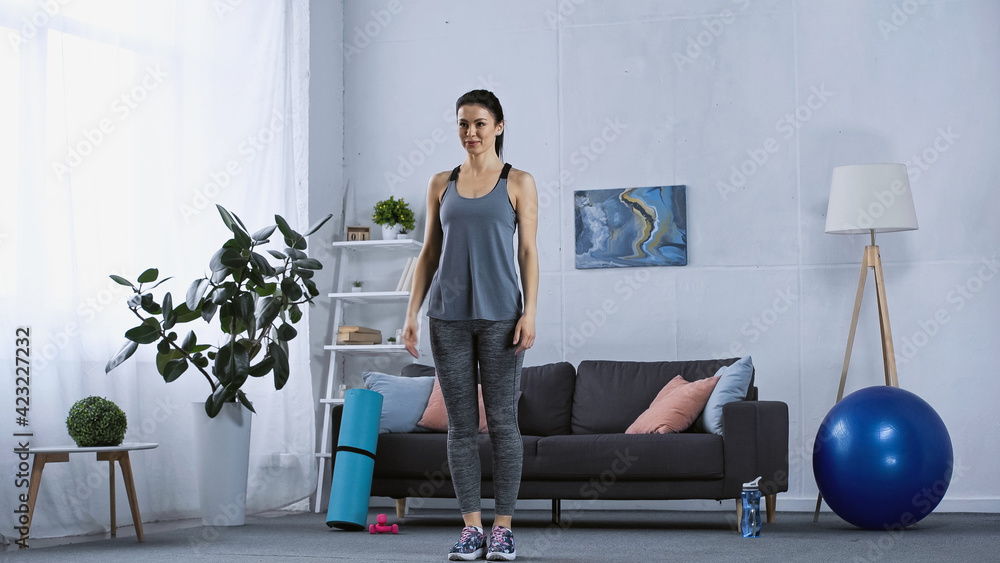 young woman in sportswear standing in modern living room