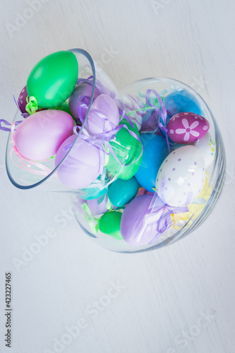 Glass vase filled with colorful Easter eggs 