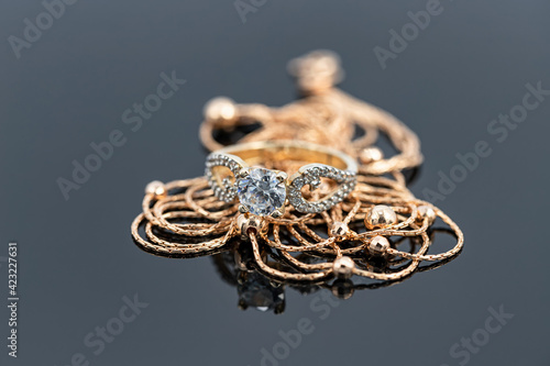 A gold chain with gold beads weave and a large diamond ring