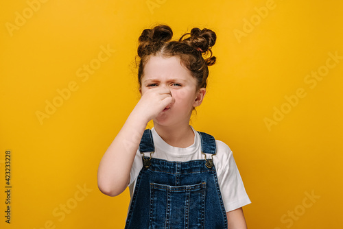 Fototapeta Unhappy sad little preschool girl kid feeling bad and dislike smell and hold nos
