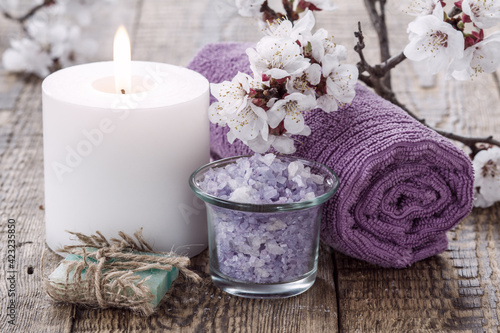 Soap, sea salt with towel and burning candle with flowering branch