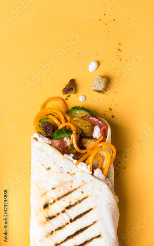 shawerma, shawarma tourtilla wrap with onion, tomato, lettuce and garilc sauce on orange background photo