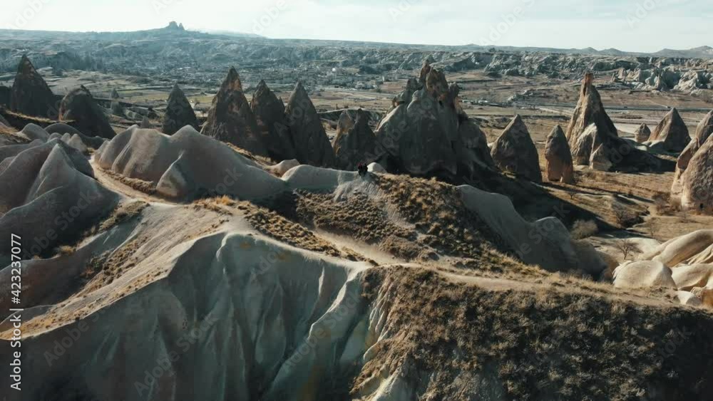 Aerial View of a Couple standing on a cliff in Cappadocia Turkey. Couple admiring nature in Goreme Cappadocia 4K Aerial Cinematic View. Aerial View of a Couple standing on a cliff in Cappadocia Turkey. Couple admiring nature in Goreme Cappadocia 4K Aerial Cinematic View.
