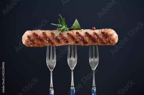 Close up of long grilled kebab on tree forks. Chevapi or chevapchici or kebapche. Copy space poster cobcept. photo