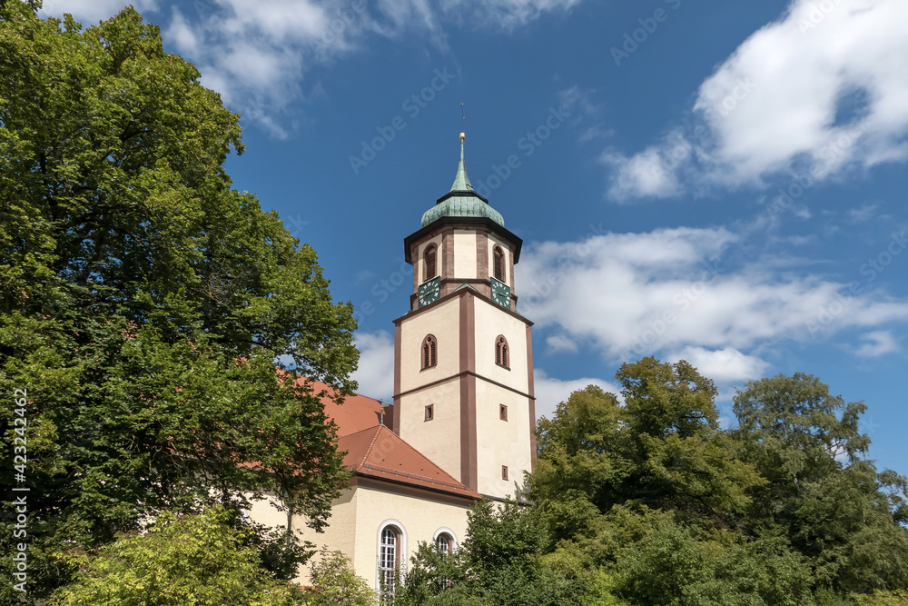 Malerischer Kirchturm hinter großen Laubbäumen im sonnigen Sommer - evangelische Martin-Luther-Kirche in Trossingen, Deutschland