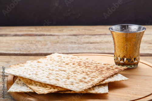 On a round wooden board matzah and a glass of kiddush wine.