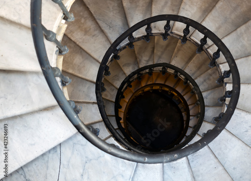 Old spiral staircase with marble steps and wrought iron handrail