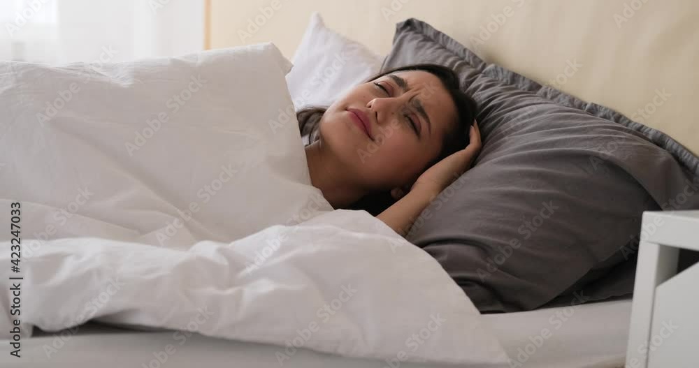 Annoyed woman trying to oversleep after waking up in bed at home Annoyed woman trying to oversleep after waking up in bed at home