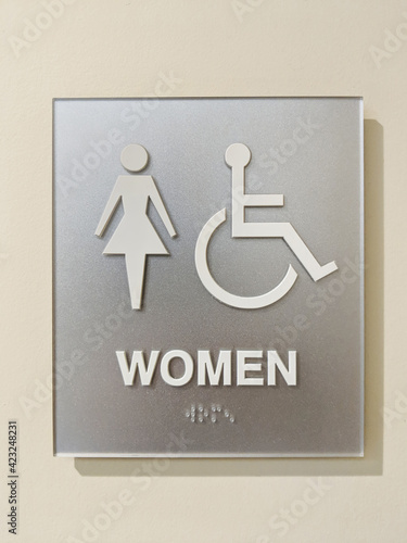 Womens ADA accessible bathroom sign with braille on wall. photo