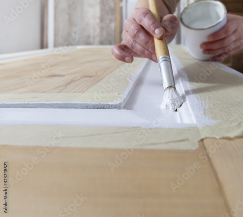 wood crafts, close up hands woman artisan carpenter painting with brush and paint jar white the door in workshop, wearing overall, interior designer, restoration, diy and handmade works concept