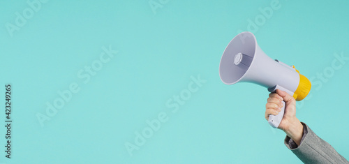 Hand is hold megaphone and wear grey suit on green or mint or Tiffany Blue  background. photo