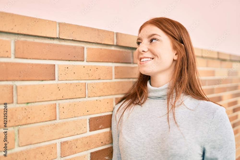 Young irish teenager girl smiling happy leaning on the wall at the city. Young irish teenager girl smiling happy leaning on the wall at the city.