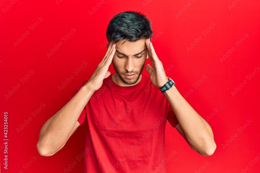 Young handsome man wearing casual tshirt over red background with hand on head, headache because stress. suffering migraine. Young handsome man wearing casual tshirt over red background with hand on head, headache because stress. suffering migraine.