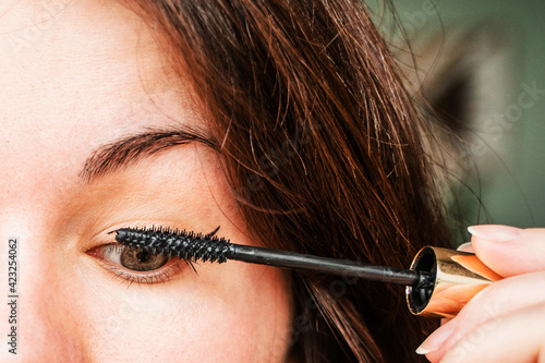 A young woman is doing makeup. Girl paints her eyelashes with mascara