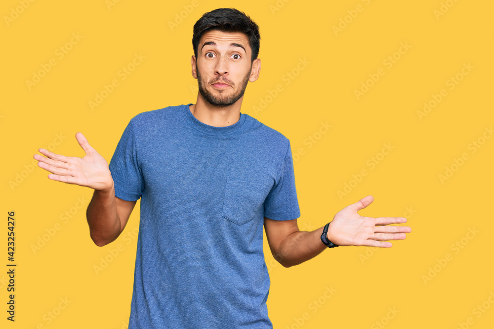 Young handsome man wearing casual clothes clueless and confused expression with arms and hands raised. doubt concept. Young handsome man wearing casual clothes clueless and confused expression with arms and hands raised. doubt concept.