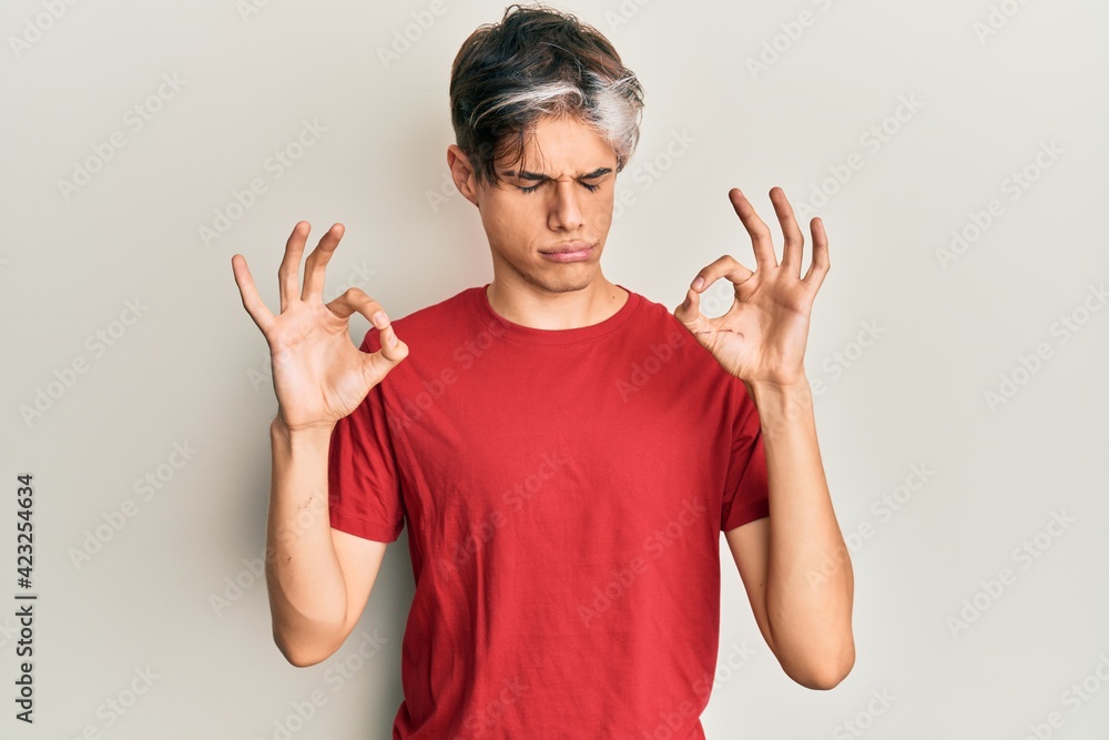 Young hispanic man wearing casual clothes relaxed and smiling with eyes closed doing meditation gesture with fingers. yoga concept. Young hispanic man wearing casual clothes relaxed and smiling with eyes closed doing meditation gesture with fingers. yoga concept.