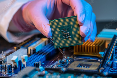 Foto Engineer's gloved hand is holding the CPU chip on the background of the motherboard