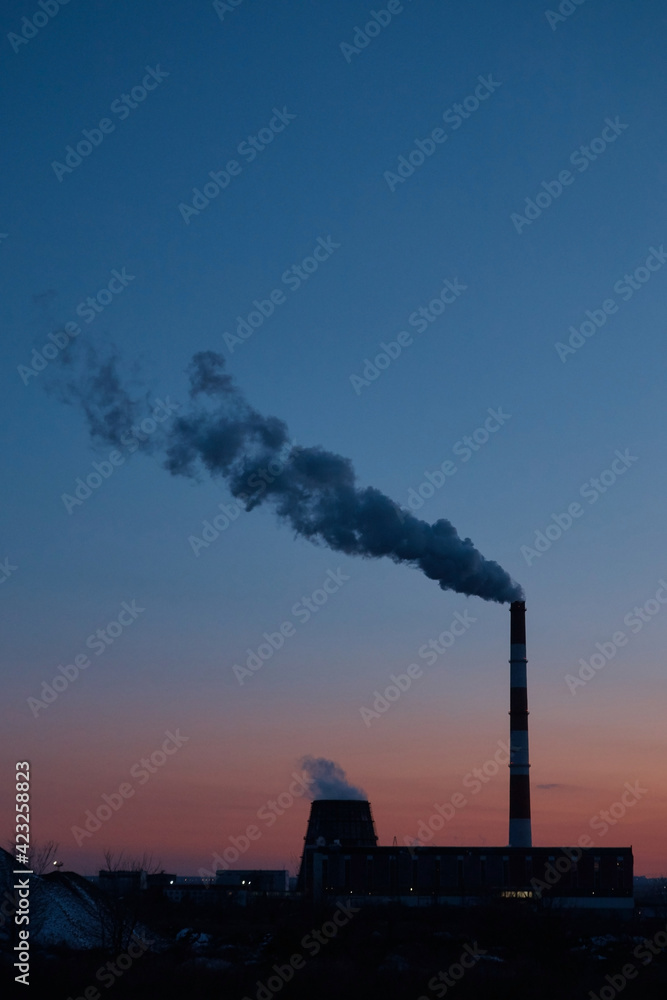 Factory from afar, steam coming from the pipe, industrial zone at sunset Factory from afar, steam coming from the pipe, industrial zone at sunset