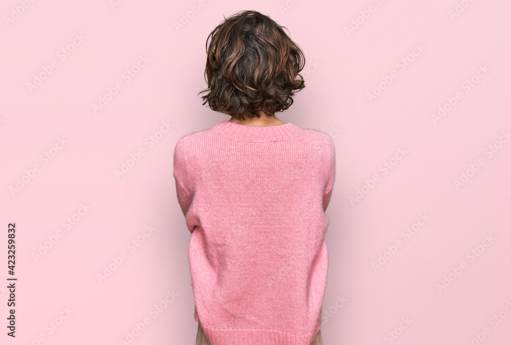 Young hispanic woman wearing casual clothes standing backwards looking away with crossed arms Young hispanic woman wearing casual clothes standing backwards looking away with crossed arms