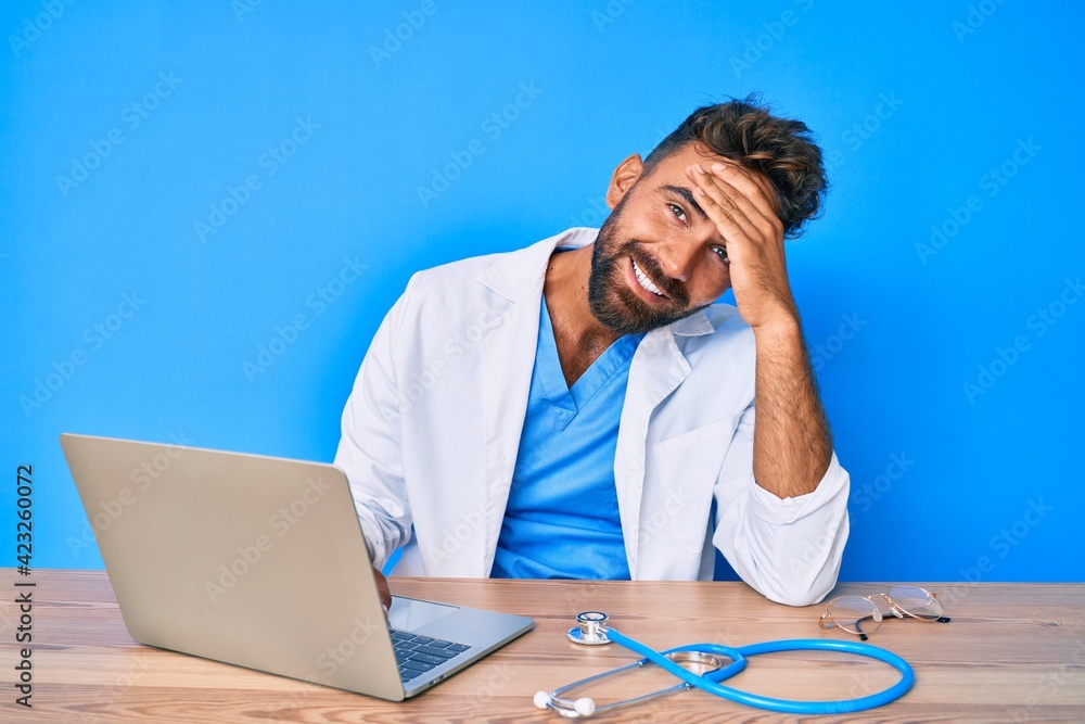 Young hispanic man wearing doctor uniform working at the clinic stressed and frustrated with hand on head, surprised and angry face Young hispanic man wearing doctor uniform working at the clinic stressed and frustrated with hand on head, surprised and angry face