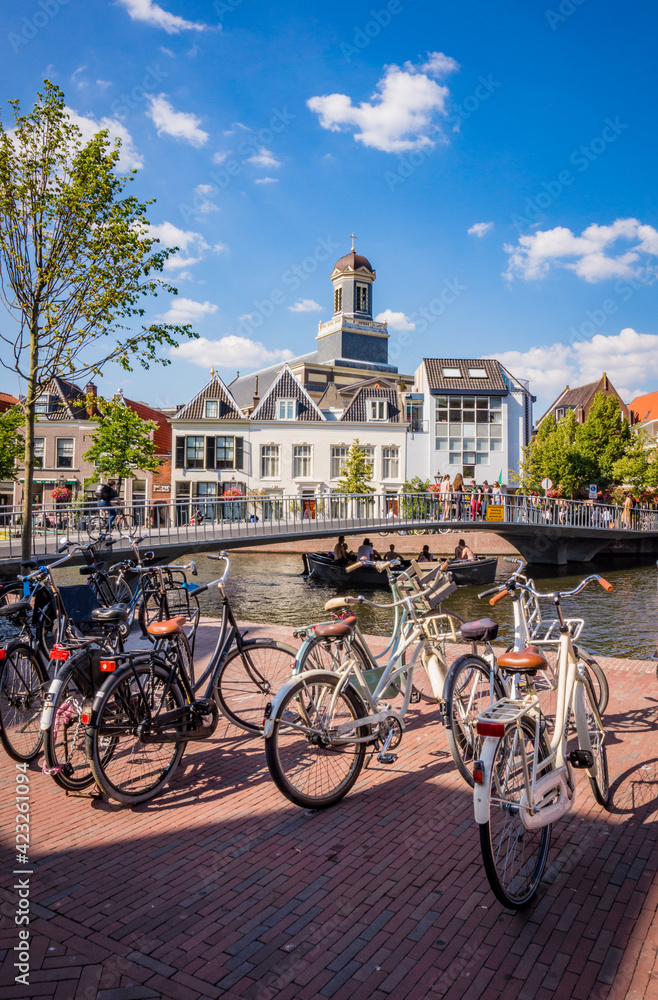 Bunch of bicycles standing by a canal next to a bridge in Leiden, the Netherlands