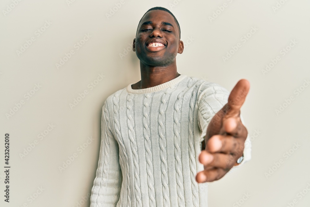 Young african american man wearing casual clothes smiling cheerful offering palm hand giving assistance and acceptance. Young african american man wearing casual clothes smiling cheerful offering palm hand giving assistance and acceptance.