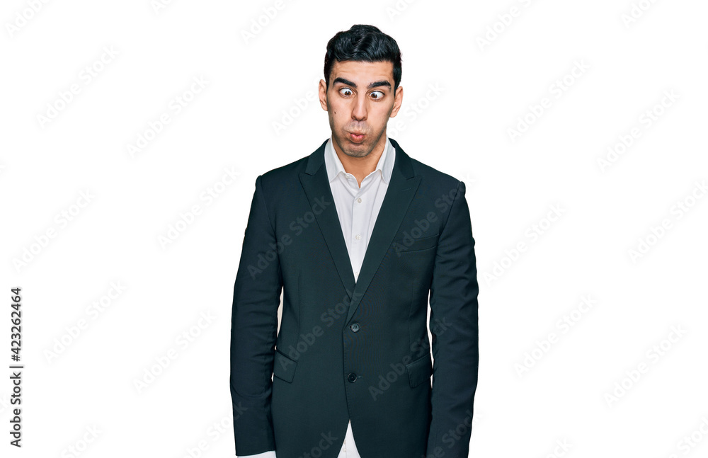 Handsome hispanic man wearing business clothes making fish face with lips, crazy and comical gesture. funny expression.