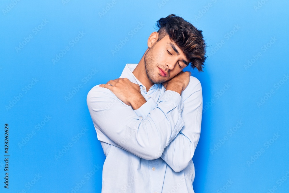 Young hispanic man wearing casual clothes hugging oneself happy and positive, smiling confident. self love and self care Young hispanic man wearing casual clothes hugging oneself happy and positive, smiling confident. self love and self care