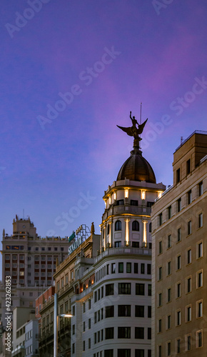 Phoenix sculpture on top of Gran Via 68 building in Madrid, with a purple sunset sky in the background 